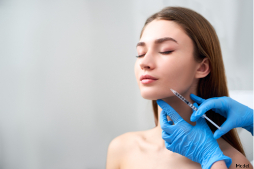 a young adult woman receiving an injection in her cheek by two gloved hands